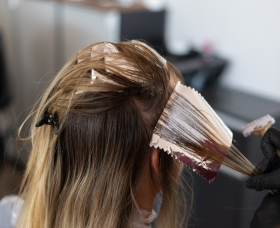 Hair coloring process in royal nails salon, showcasing stylist applying color to client's hair.